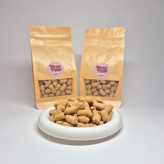 Resealable pouches of Meow Plaza rabbit freeze dried treats behind a plate showcasing the structure of the cat treats